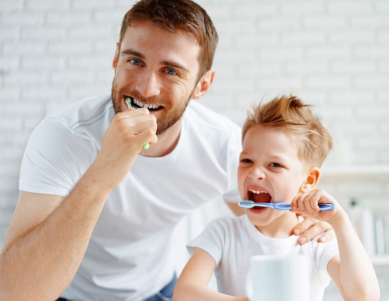 Dad and son brushing their teeth together